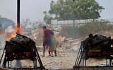 Family members of COVID-19 victims leave as their funeral pyres burn at an open crematorium set up at a granite quarry on the outskirts of Bengaluru, India, May 5, 2021. (Aijaz Rahi/AP)
