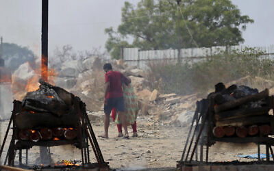 Family members of COVID-19 victims leave as their funeral pyres burn at an open crematorium set up at a granite quarry on the outskirts of Bengaluru, India, May 5, 2021. (Aijaz Rahi/AP)