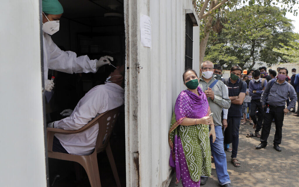 A health worker takes a nasal swab sample of a person to test for COVID-19 as others wait for their turn outside a field hospital in Mumbai, India, Thursday, May 6, 2021. Infections in India hit another grim daily record on Thursday as demand for medical oxygen jumped seven-fold and the government denied reports that it was slow in distributing life-saving supplies from abroad. (AP Photo/Rajanish kakade) A health worker takes a nasal swab sample of a person to test for COVID-19 as others wait for their turn outside a field hospital in Mumbai, India, Thursday, May 6, 2021. Infections in India hit another grim daily record on Thursday as demand for medical oxygen jumped seven-fold and the government denied reports that it was slow in distributing life-saving supplies from abroad. (AP Photo/Rajanish kakade)