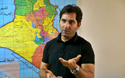 Raslan Haddad, the presenter of the local TV prank show, Tannab Raslan, stands in front of a map of Iraq during an interview with The Associated Press in Baghdad, Iraq, Tuesday, May. 5, 2021. (AP/Hadi Mizban)