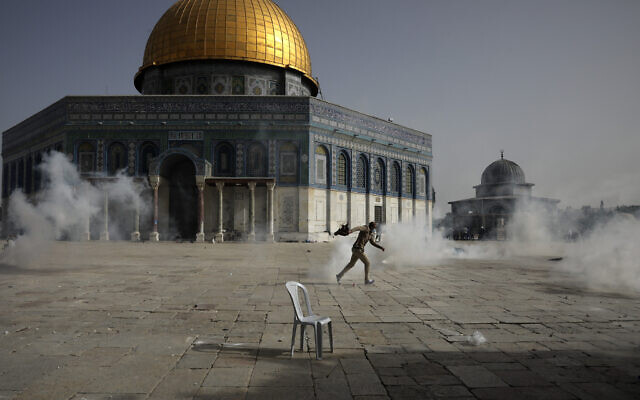 A Palestinian man runs away from tear gas during clashes with Israeli security forces in front of the Dome of the Rock Mosque at the Al Aqsa Mosque compound in Jerusalem's Old City, on May 10, 2021. (AP/Mahmoud Illean) A Palestinian man runs away from tear gas during clashes with Israeli security forces in front of the Dome of the Rock Mosque at the Al Aqsa Mosque compound in Jerusalem's Old City, on May 10, 2021. (AP/Mahmoud Illean)