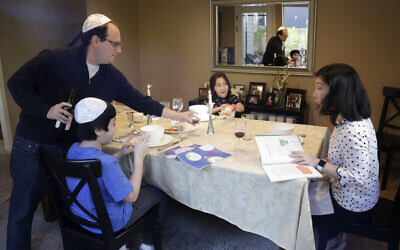 Seth Pollack pours wine for his family, wife Jessica Choe and children Micah and Mina Pollack, as they being their Passover meal in Seattle, April 8, 2020 (AP Photo/Elaine Thompson)