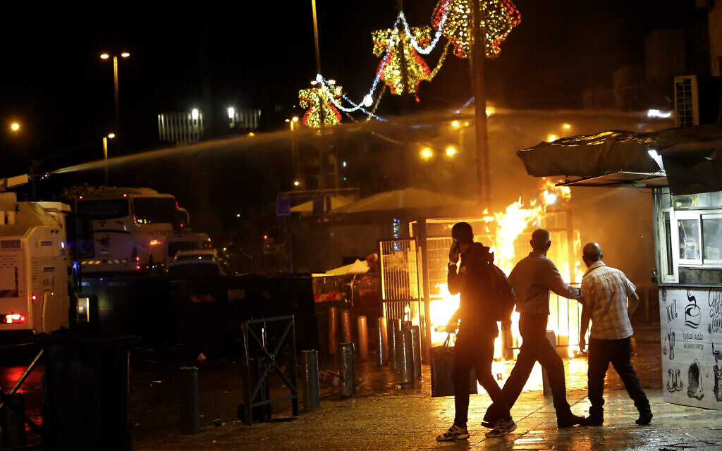 An Israeli police water cannon is deployed near the Damascus Gate to the Old City of Jerusalem as a fire burns during clashes between police and Palestinian protesters Monday, May 10, 2021. (AP Photo/Mahmoud Illean)