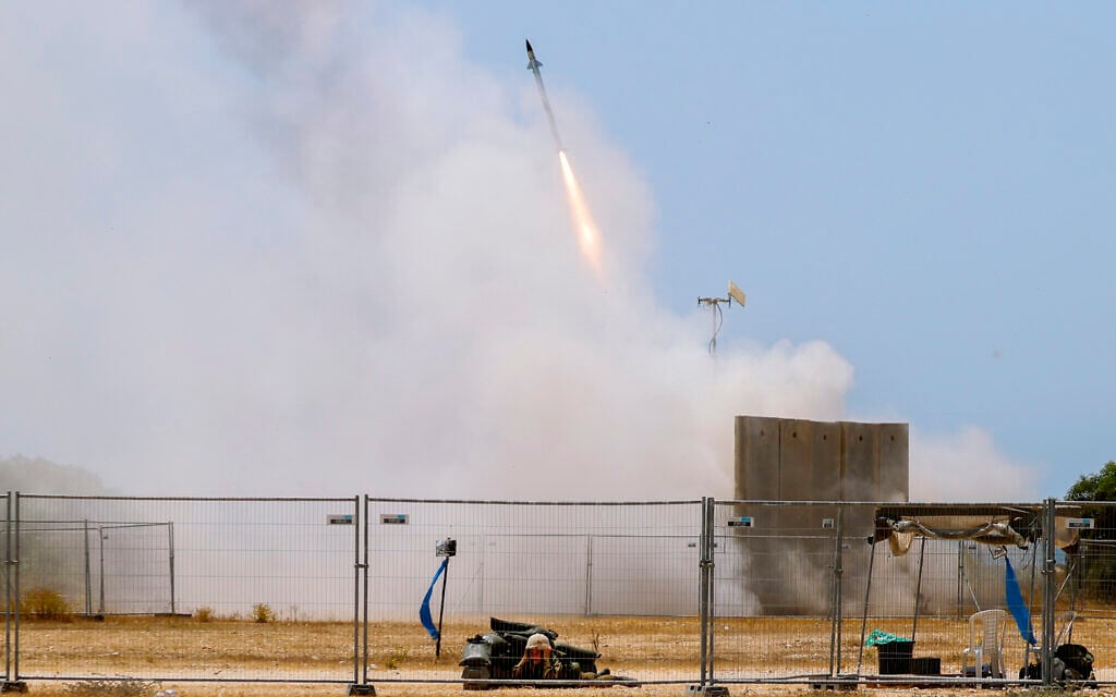 A Israeli soldier takes cover as an Iron Dome air defense system launches to intercept a rocket from the Gaza Strip, in southern Israel, May 11, 2021. (AP Photo/Ariel Schalit)