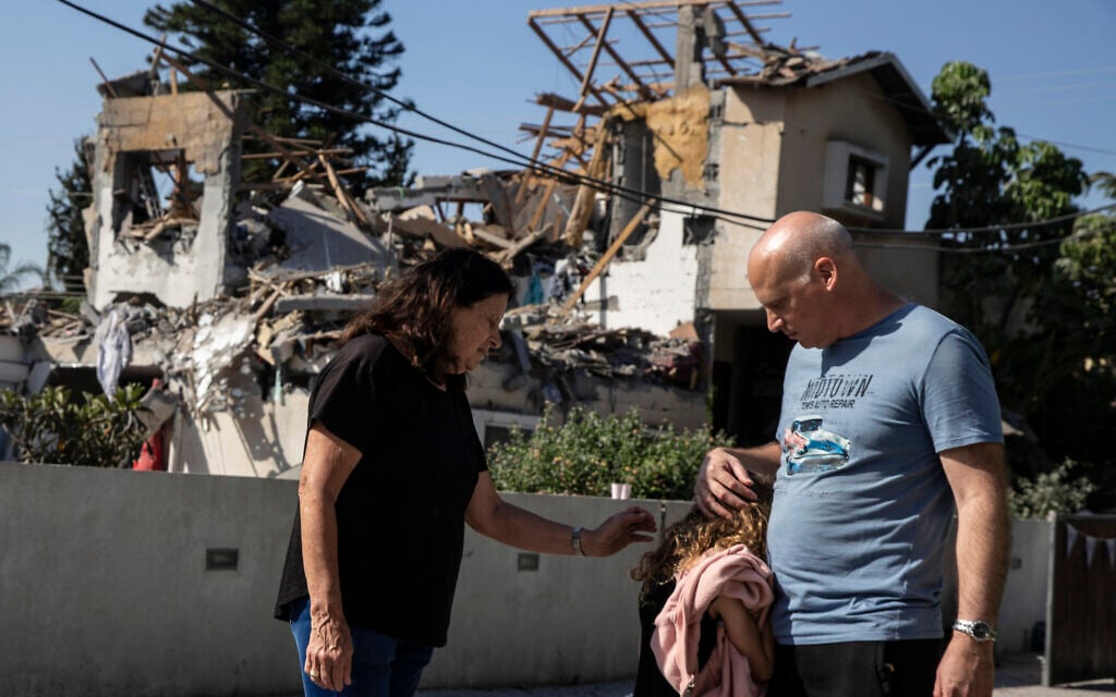 A young girl is comforted by her father next to a house damaged by a rocket fired from the Gaza Strip, in Yehod, central Israel, May 12, 2021 (AP Photo/Heidi Levine)