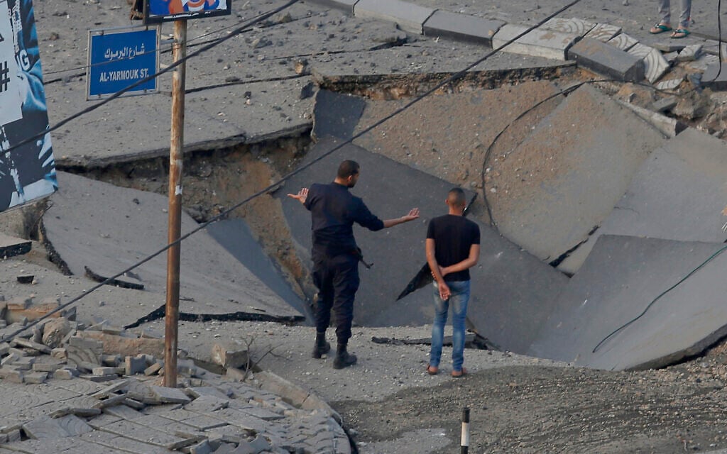 People stand on a destroyed street after an Israeli air strike hit previous day in Gaza City in response to rocket fire, May 13, 2021 (AP Photo/Hatem Moussa)