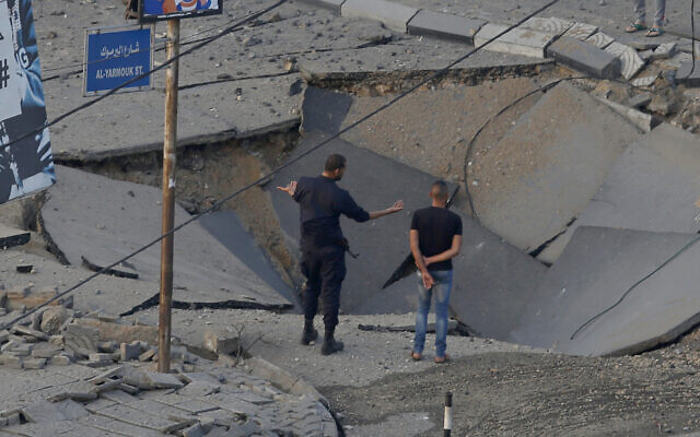 People stand on a destroyed street after an Israeli air strike hit previous day in Gaza City in response to rocket fire, May 13, 2021 (AP Photo/Hatem Moussa) People stand on a destroyed street after an Israeli air strike hit previous day in Gaza City in response to rocket fire, May 13, 2021 (AP Photo/Hatem Moussa)