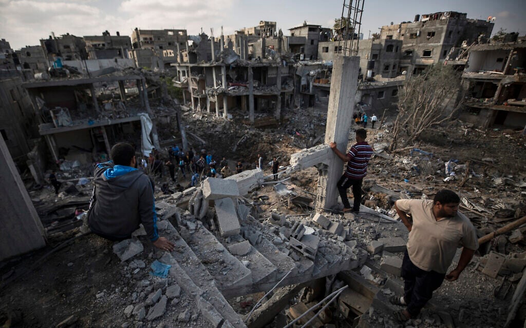 Palestinians inspect destroyed buildings following overnight Israeli airstrikes in Beit Hanoun, in the northern Gaza Strip, May 14, 2021. (AP Photo/Khalil Hamra)