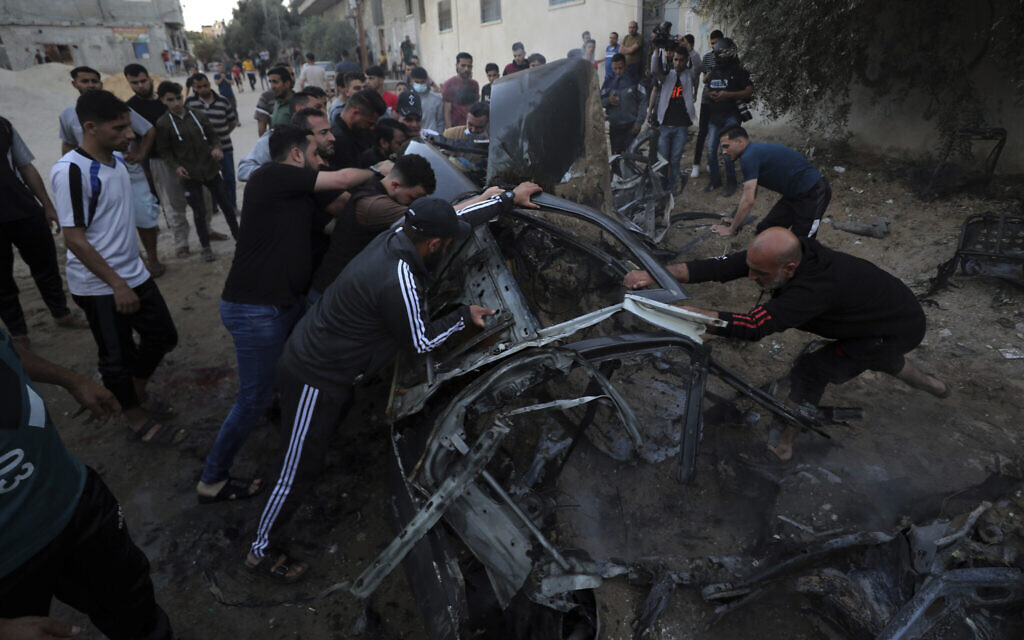 Palestinians gather around a car after it was hit by an Israeli airstrike in retaliation for rocket fire, in Gaza City, May 15, 2021. (AP Photo/Mohammed Ali)
