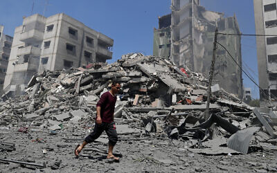 A man walks past the the rubble of the Yazegi residential building that was destroyed by an Israeli airstrike, in Gaza City, Sunday, May 16, 2021.  (AP Photo/Adel Hana)