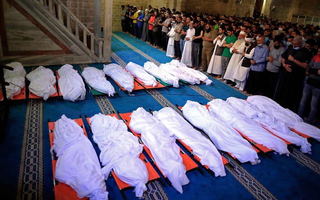 Mourners pray over the bodies of 17 Palestinians who were killed in overnight Israeli airstrikes in Gaza City, Sunday, May 16, 2021. (AP/Sanad Latifa)