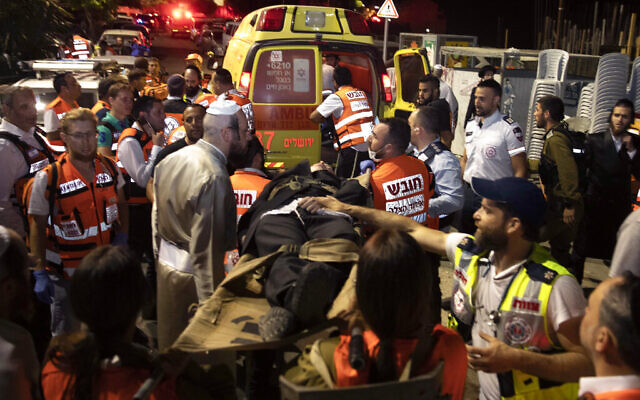 Israeli medics carry wounded ultra-Orthodox men outside a synagogue in Givat Zeev, outside Jerusalem, Sunday, May 16, 2021. More than 150 people were injured in a fatal collapse of a bleacher at an uncompleted West Bank synagogue. (AP Photo/Sebastian Scheiner) Israeli medics carry wounded ultra-Orthodox men outside a synagogue in Givat Zeev, outside Jerusalem, Sunday, May 16, 2021. More than 150 people were injured in a fatal collapse of a bleacher at an uncompleted West Bank synagogue. (AP Photo/Sebastian Scheiner)