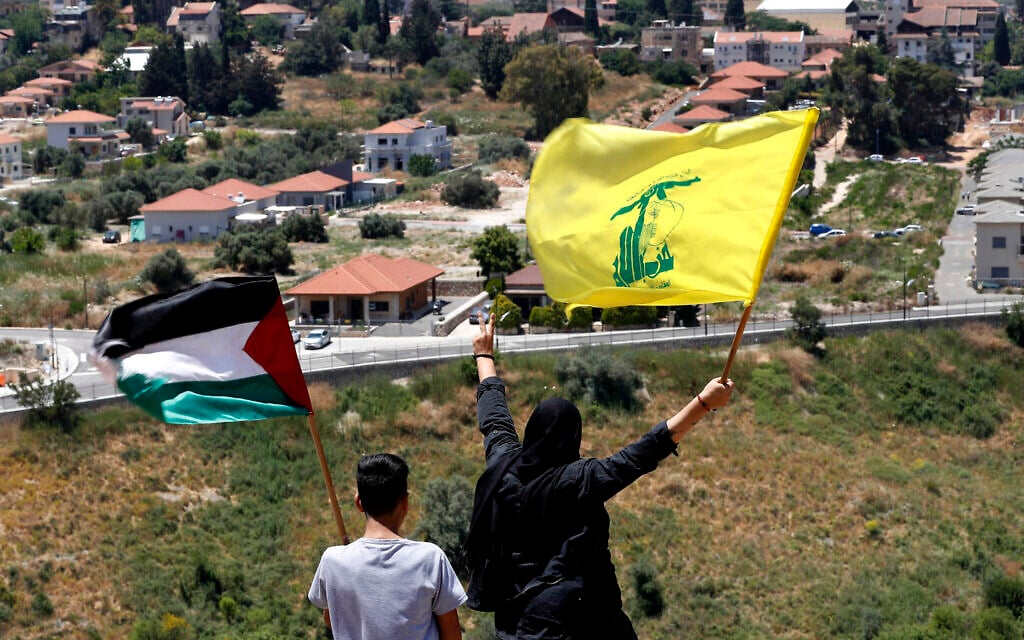 In this May 15, 2021, file photo, Lebanese wave Hezbollah and Palestinian flags, as they stand in front of the Israeli town of Metula, background, on the Lebanese side of the Lebanese-Israeli border in the southern village of Kfar Kila, Lebanon. (AP Photo/Hussein Malla, File) In this May 15, 2021, file photo, Lebanese wave Hezbollah and Palestinian flags, as they stand in front of the Israeli town of Metula, background, on the Lebanese side of the Lebanese-Israeli border in the southern village of Kfar Kila, Lebanon. (AP Photo/Hussein Malla, File)