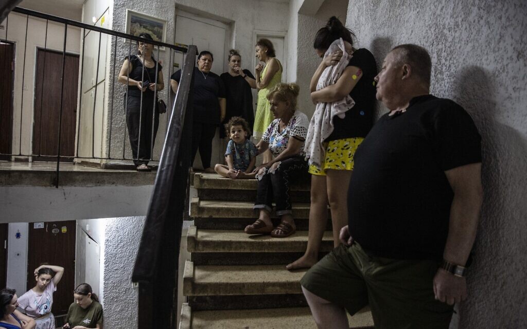 Israelis take shelter in the stairwell of their apartment building as a siren sounds a warning of incoming rockets fired from the Gaza Strip, In Ashdod, Wednesday, May 19, 2021. (AP Photo/Heidi Levine)