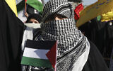 Illustrative: A woman covers her face in the style of Palestinian and Lebanese militants as she holds a Palestinian flag in a pro-Palestinians gathering in Tehran, Iran, May 19, 2021. (AP Photo/Vahid Salemi)