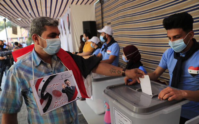 A Syrian man who lives in Lebanon hangs on his chest a portrait of Syrian president Bashar Assad, as he casts his ballot for his country's presidential election at the Syrian embassy in Yarze, east of Beirut, Lebanon, May 20, 2021. (Hussein Malla/AP) A Syrian man who lives in Lebanon hangs on his chest a portrait of Syrian president Bashar Assad, as he casts his ballot for his country's presidential election at the Syrian embassy in Yarze, east of Beirut, Lebanon, May 20, 2021. (Hussein Malla/AP)