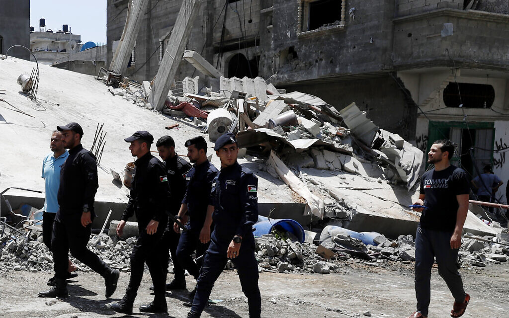 Police officers from Gaza's ruling Hamas terror group near a destroyed residential building which was hit by Israeli airstrikes after rocket fire from Gaza, in Beit Lahiya, Gaza Strip, Thursday, May 20, 2021. (AP/Adel Hana)