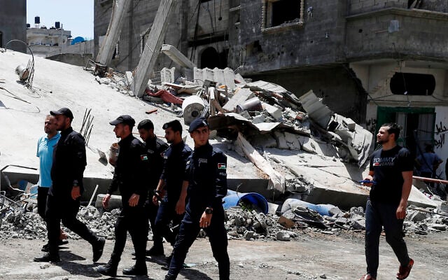 Police officers from Gaza's ruling Hamas terror group near a destroyed residential building which was hit by Israeli airstrikes after rocket fire from Gaza, in Beit Lahiya, Gaza Strip, Thursday, May 20, 2021. (AP/Adel Hana) Police officers from Gaza's ruling Hamas terror group near a destroyed residential building which was hit by Israeli airstrikes after rocket fire from Gaza, in Beit Lahiya, Gaza Strip, Thursday, May 20, 2021. (AP/Adel Hana)
