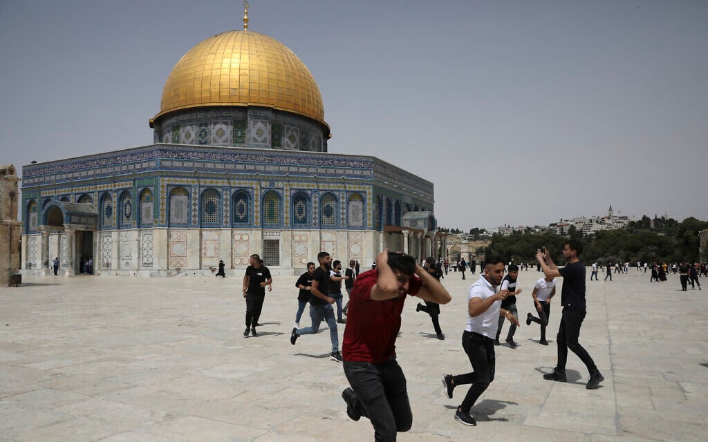 Palestinians run from sound bombs thrown by Israeli police in front of the Dome of the Rock shrine at the al-Aqsa mosque complex in Jerusalem, Friday, May 21, 2021. (AP Photo/Mahmoud Illean)