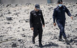 Hamas police walk through debris from a destroyed building that was hit by an airstrike previous to a ceasefire reached after an 11-day war between Gaza's Hamas rulers and Israel, in Gaza City, Saturday, May 22, 2021. (AP Photo/John Minchillo)