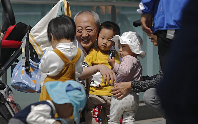 An elderly man plays with children near a commercial office building in Beijing on May 10, 2021. (AP Photo/Andy Wong) An elderly man plays with children near a commercial office building in Beijing on May 10, 2021. (AP Photo/Andy Wong)