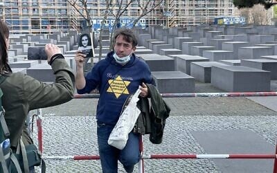 Illustrative: A man protests coronavirus restrictions with a yellow star and a photo of Anne Frank outside the Holocaust memorial in Berlin. (@ZSKberlin/Twitter via JTA)