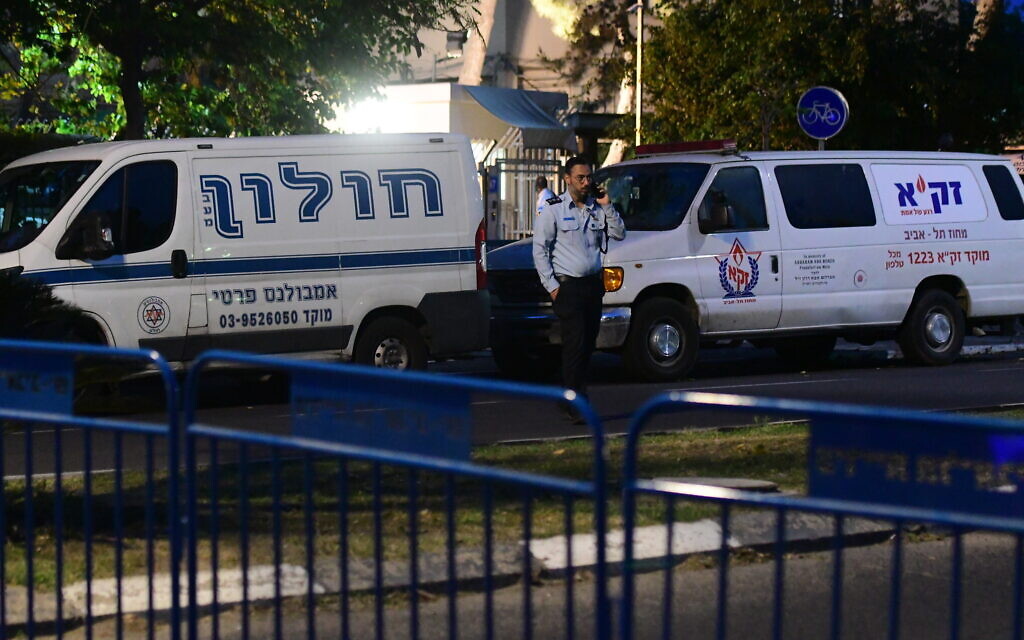 A police officer stands next to ambulances outside the Institute of Forensic Medicine in Tel Aviv, where the bodies of victims from the deadly crushing at Mount Meron are being identified, May 1, 2021. (Avshalom Sassoni/Flash90)