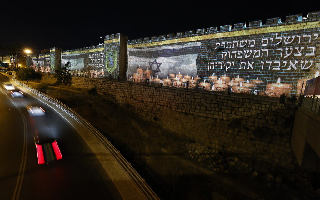 The Old City walls in Jerusalem are lit up with the Israeli flag and candles in memory of the 45 victims who were killed in fatal crushing at Mount Meron during Lag B'Omer celebrations, May 0, 2021. (Yonatan Sindel/Flash90)
