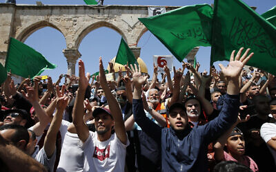 Palestinians wave flags of the Hamas terror group after afternoon prayers for the last Friday of the holy Muslim month of Ramadan, on the Temple Mount in Jerusalem's Old City, May 7, 2021. (Jamal Awad/Flash90)