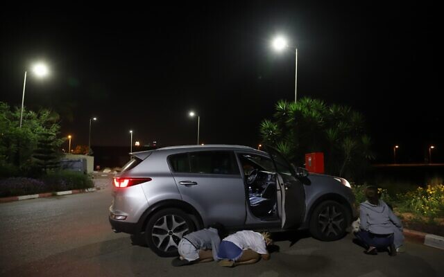 People take cover as a siren sounds a warning of incoming rockets fired from the Gaza strip, in central Israel on May 11, 2021. (Yossi Aloni/Flash90)
