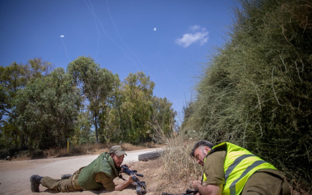 Israeli soldiers take cover near the Israeli-Gaza border as the Iron Dome anti-missile system fires interceptor missiles at rockets fired from the Gaza Strip into Israel, on May 17, 2021 (Yonatan Sindel/Flash90)