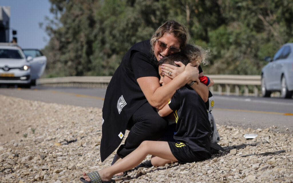 A woman and child take cover as a siren sounds a warning of incoming rockets fired from the Gaza strip in the city of Ashkelon, southern Israel, on May 19, 2021 (Olivier Fitoussi/Flash90)