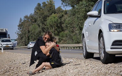 A woman and child take cover as a siren sounds a warning of incoming rockets fired from the Gaza strip in the city of Ashkelon, southern Israel, on May 19, 2021. (Olivier Fitoussi/Flash90)