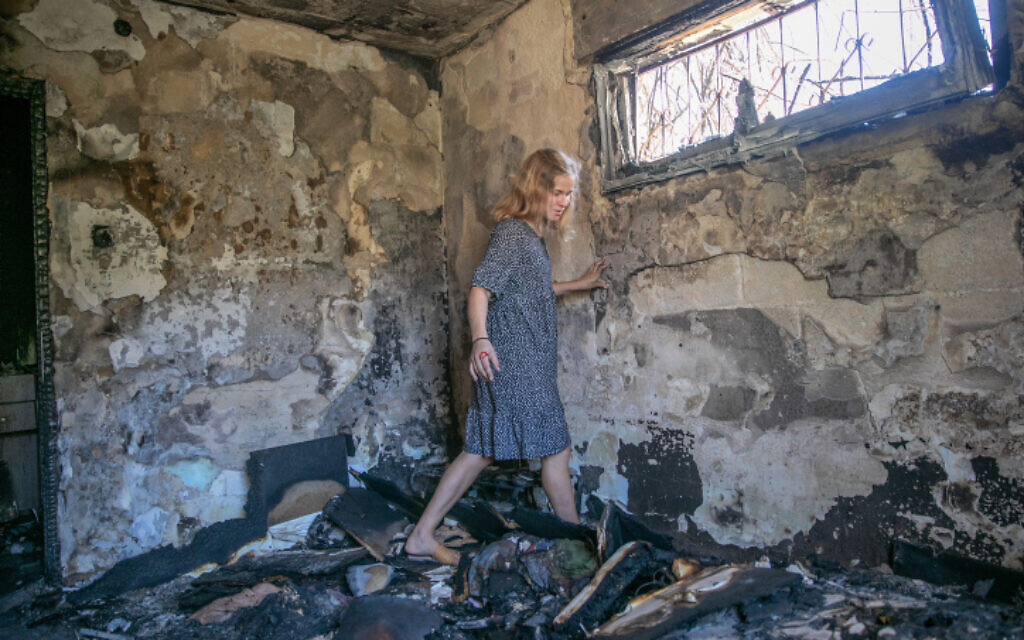 A woman walks through burnt rubble in Lod on May 19, 2021, as clean-up and rebuilding begin in the central city following riots a week earlier. (Yossi Aloni/Flash90) A woman walks through burnt rubble in Lod on May 19, 2021, as clean-up and rebuilding begin in the central city following riots a week earlier. (Yossi Aloni/Flash90)