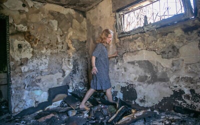 A woman walks through burnt rubble in Lod on May 19, 2021, as clean-up and rebuilding begin in the central city following riots a week earlier. (Yossi Aloni/Flash90)