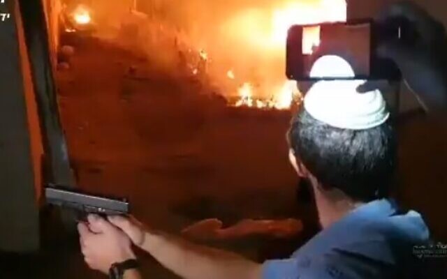 An Israeli draws his gun after a vehicle was set alight during clashes in the East Jerusalem neighborhood of Sheikh Jarrah on May 6, 22021 (Screencapture/ Twitter) An Israeli draws his gun after a vehicle was set alight during clashes in the East Jerusalem neighborhood of Sheikh Jarrah on May 6, 22021 (Screencapture/ Twitter)