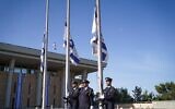 The Knesset Guard lowers Israeli flags to half-staff outside the Knesset in Jerusalem as a national day of mourning begins for victims of the Meron disaster, May 2, 2021. (Noam Moskowitz/Knesset)