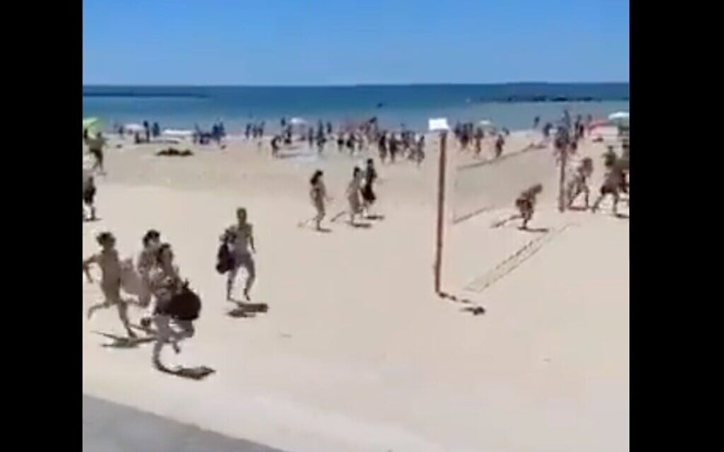 Israeli on Tel Aviv beach run for shelter as sirens signal incoming rockets from Gaza on May 15, 2021 (Twitter screenshot)
