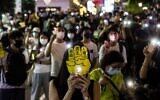 People hold up their phones with the light on in the Causeway Bay district of Hong Kong on June 4, 2021, after police closed the venue where Hong Kong people traditionally gather annually to mourn the victims of China's Tiananmen Square crackdown in 1989 which the authorities have banned citing the coronavirus pandemic and vowed to stamp out any protests on the anniversary. (ISAAC LAWRENCE / AFP)