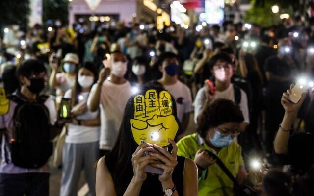 People hold up their phones with the light on in the Causeway Bay district of Hong Kong on June 4, 2021, after police closed the venue where Hong Kong people traditionally gather annually to mourn the victims of China's Tiananmen Square crackdown in 1989 which the authorities have banned citing the coronavirus pandemic and vowed to stamp out any protests on the anniversary. (ISAAC LAWRENCE / AFP) People hold up their phones with the light on in the Causeway Bay district of Hong Kong on June 4, 2021, after police closed the venue where Hong Kong people traditionally gather annually to mourn the victims of China's Tiananmen Square crackdown in 1989 which the authorities have banned citing the coronavirus pandemic and vowed to stamp out any protests on the anniversary. (ISAAC LAWRENCE / AFP)