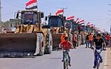 Palestinian boys cycle past a convoy of bulldozers provided by Egypt arriving at the Palestinian side of the Rafah border crossing between Egypt and the Palestinian Gaza Strip enclave on June 4, 2021 (SAID KHATIB / AFP)