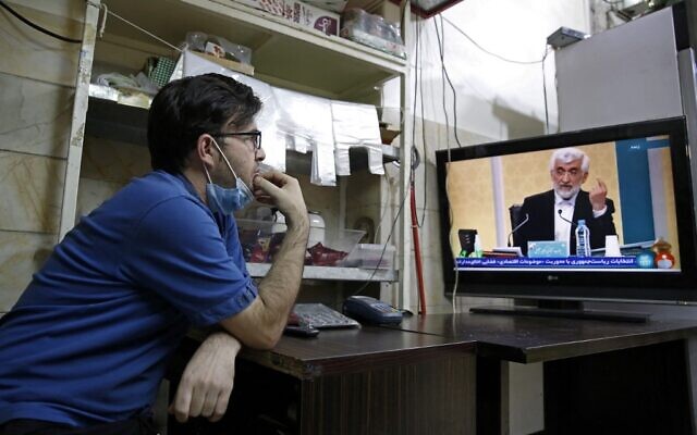 An Iranian vendor watches candidate Saeed Jalili speaking during the first televised debate between Iran presidential candidates, at a shop in Tehran on June 5, 2021. (AFP) An Iranian vendor watches candidate Saeed Jalili speaking during the first televised debate between Iran presidential candidates, at a shop in Tehran on June 5, 2021. (AFP)