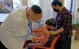 A young teen receives a dose of the Pfizer-BioNTech Covid-19 vaccine at the Misgav Ladach hospital in Jerusalem on June 6, 2021, as Israel begins its coronavirus vaccination campaign for 12- to 15-year-olds. (Menahem KAHANA/AFP)