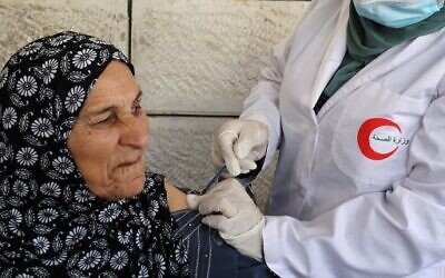 A Palestinian member of a health ministry mobile unit vaccinates an elderly Palestinian against the COVID-19 coronavirus, in the village of Dura near Hebron in the West Bank, on June 9, 2021. (Photo by HAZEM BADER / AFP)