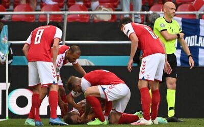 Denmark players help Denmark's midfielder Christian Eriksen after he collapsed before the medics arrive during the UEFA EURO 2020 Group B football match between Denmark and Finland at the Parken Stadium in Copenhagen on June 12, 2021. (Jonathan NACKSTRAND / various sources / AFP)