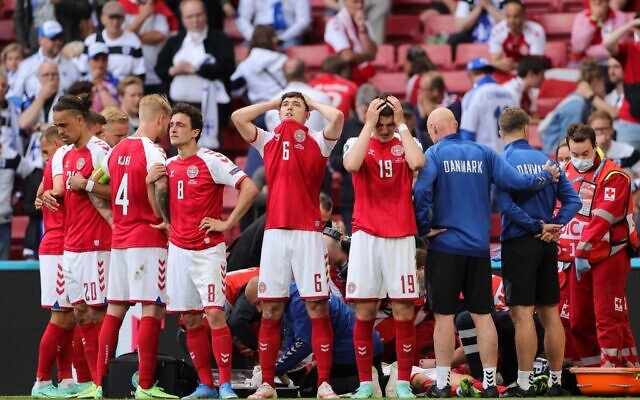 Denmark's players react and form a protective screen as paramedics attend to Denmark's midfielder Christian Eriksen after he collapsed on the pitch during the UEFA EURO 2020 Group B football match between Denmark and Finland at the Parken Stadium in Copenhagen on June 12, 2021. (Friedemann Vogel / POOL / AFP)