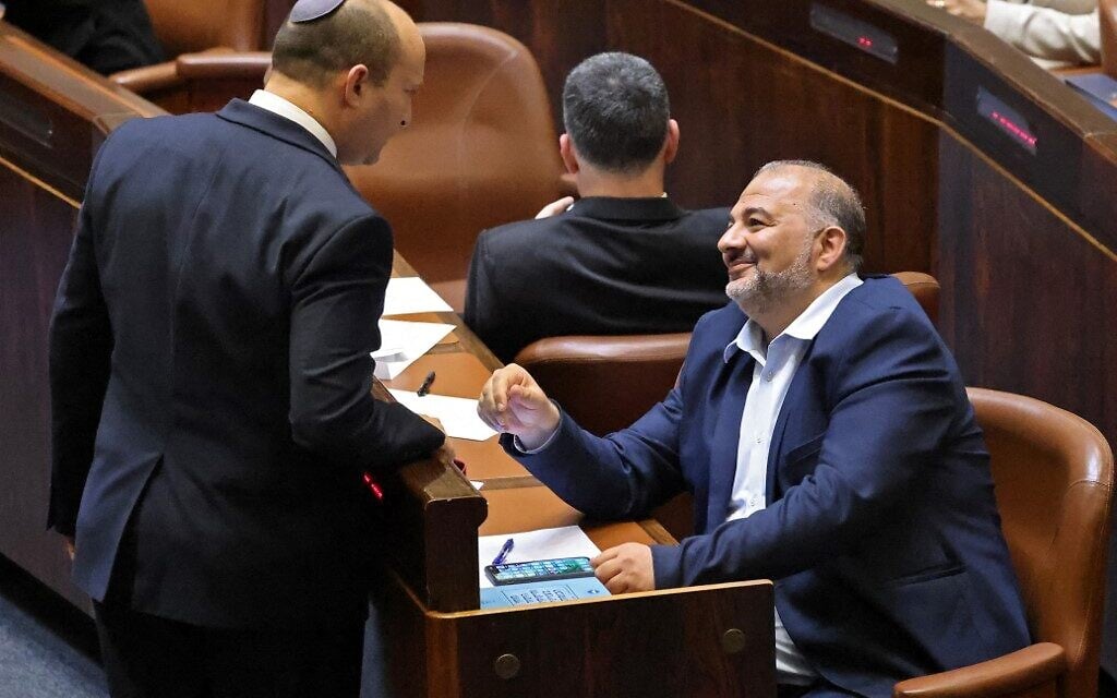 Prime Minister Naftali Bennett (L) talks with Mansour Abbas, head of the Islamic Ra'am Party, during a special session to vote on the new government at the Knesset in Jerusalem, on June 13, 2021. (EMMANUEL DUNAND/AFP)