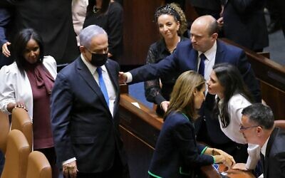 Prime Minister Benjamin Netanyahu, loser of a recent election, walks away after briefly shaking hands with new Prime Minister Naftali Bennett, after the Knesset voted confidence in Bennett's coalition by 60-59 votes, June 13, 2021. (Emmanuel Dunand / AFP)