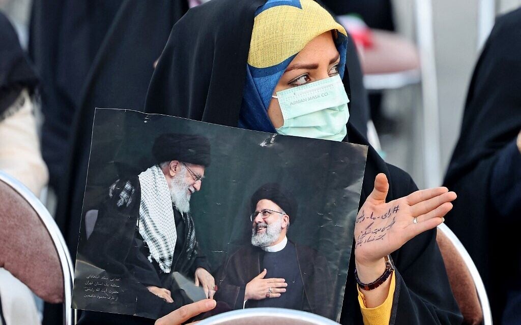 A supporter of Iranian presidential candidate Ebrahim Raisi holds a picture of him with Iran's Supreme Leader Ayatollah Ali Khamenei during an election campaign rally in the capital Tehran, on June 14, 2021. (Photo by ATTA KENARE / AFP) A supporter of Iranian presidential candidate Ebrahim Raisi holds a picture of him with Iran's Supreme Leader Ayatollah Ali Khamenei during an election campaign rally in the capital Tehran, on June 14, 2021. (Photo by ATTA KENARE / AFP)