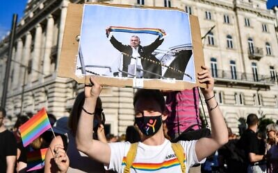 A participant holds a placard showing Hungarian Prime Minister Viktor Orban holding a scarf in rainbow colors, in front of the parliament building in Budapest on June 14, 2021, during a demonstration against the Hungarian government's draft bill seeking to ban the "promotion" of homosexuality and sex changes. (Photo by GERGELY BESENYEI / AFP)